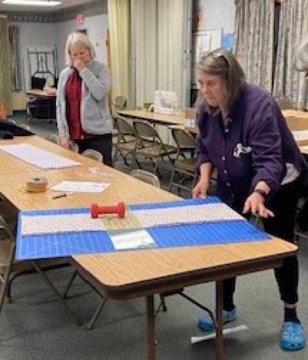 Pat Lemay watches Gail O'Brien prepare to cut the fabric for another dress.